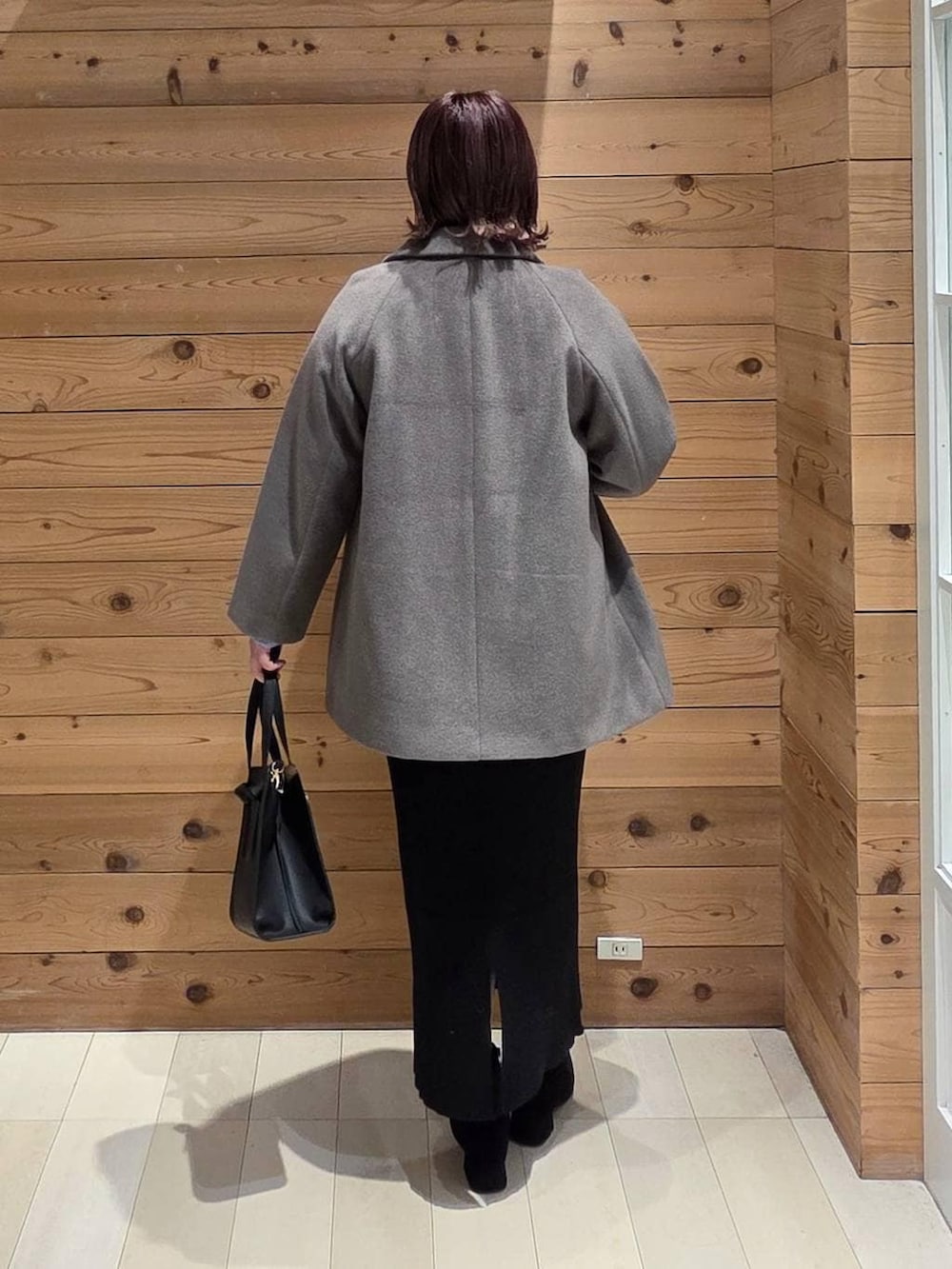 ブラック系のショルダーバッグ、ブラウン系のチェスターコート、ホワイト系のTシャツ/カットソーを着用したレディースの冬コーディネートの3枚目の写真