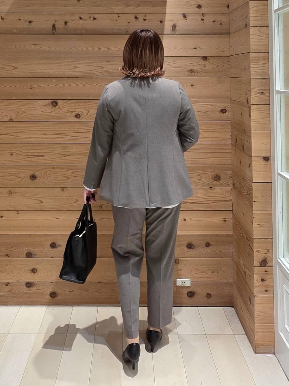 ブラック系のパンプス、ブラウン系のスラックス、ブルー系のセットアップを着用したレディースの冬コーディネートの3枚目の写真