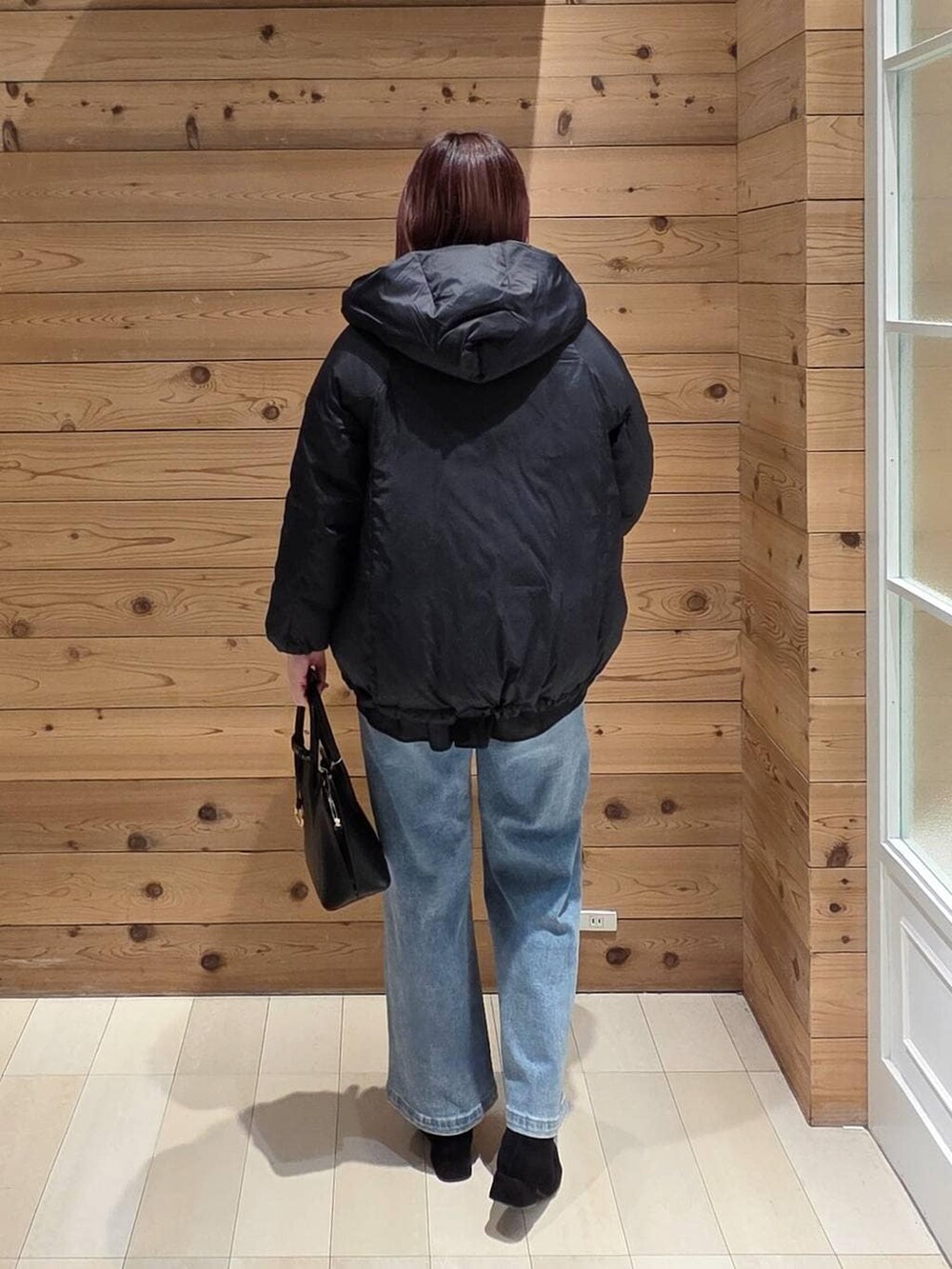 ブラック系のショルダーバッグ、ブラック系のダウンジャケット/コート、ブラック系のTシャツ/カットソーを着用したレディースの冬コーディネートの3枚目の写真