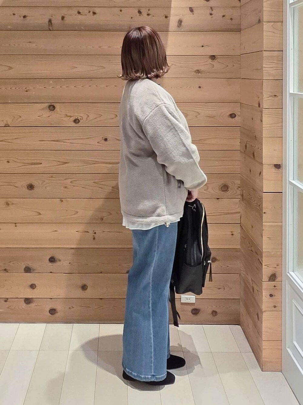 ブラウン系のブルゾン、ブラック系のバックパック/リュック、ホワイト系のTシャツ/カットソーを着用したレディースの冬コーディネートの2枚目の写真