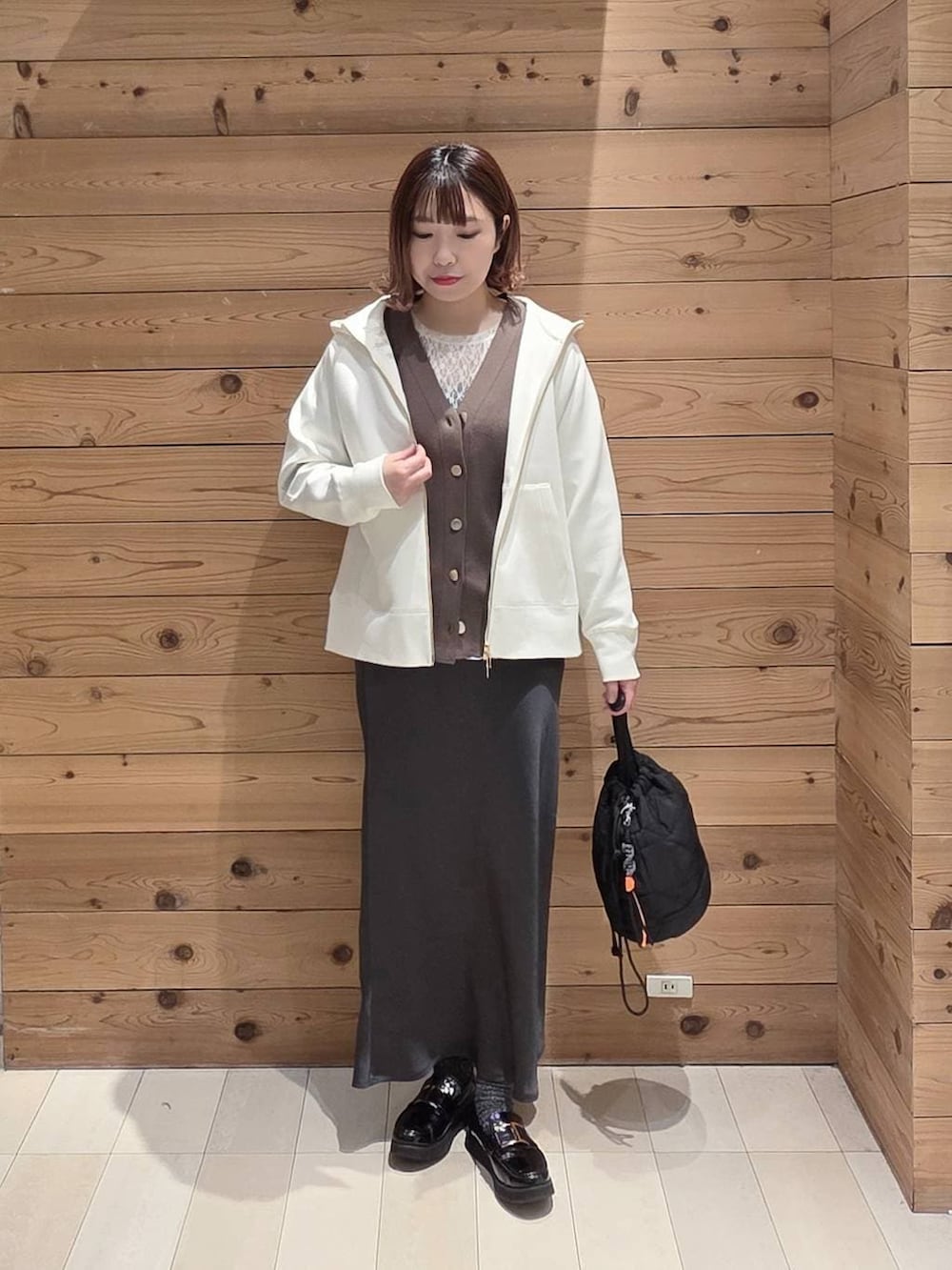 ブラック系のローファー、ブラック系のハンドバッグ、ホワイト系のパーカーを着用したレディースの春コーディネートの4枚目の写真