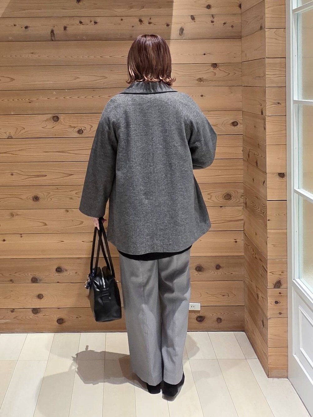 ブラック系のボストンバッグ、グレー系のチェスターコート、ブラック系のニット/セーターを着用したレディースの冬コーディネートの3枚目の写真