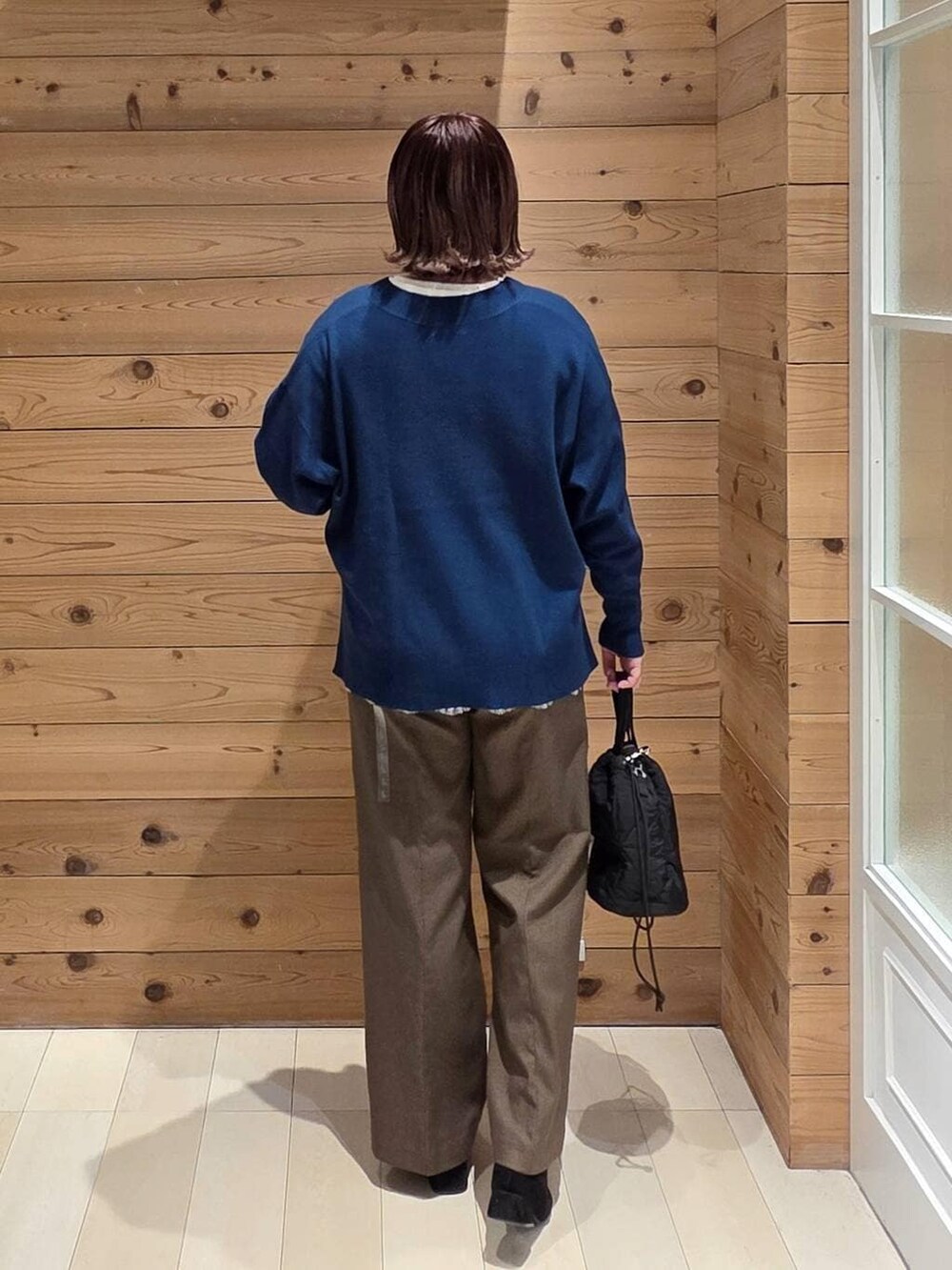 ベージュ系のダウンジャケット/コート、ブラック系のハンドバッグ、ブルー系のニット/セーターを着用したレディースの冬コーディネートの3枚目の写真