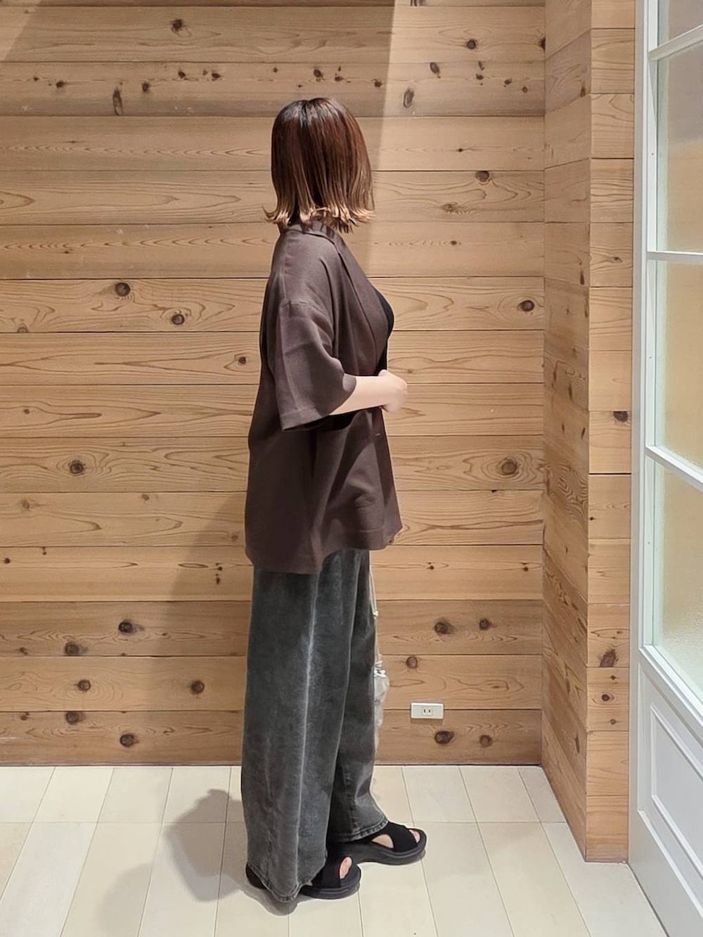 ブラック系のデニムパンツ、ブラウン系のテーラードジャケット、ブラック系のタンクトップを着用したレディースの夏コーディネートの2枚目の写真