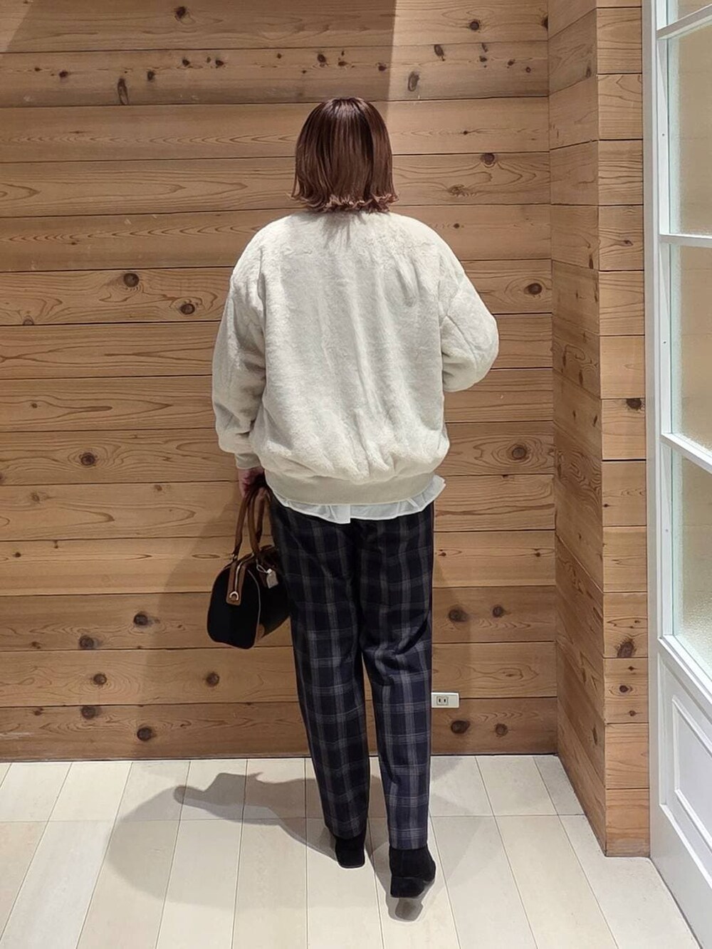 ベージュ系のブルゾン、ブラック系のスウェット、ブルー系のその他パンツを着用したレディースの冬コーディネートの3枚目の写真