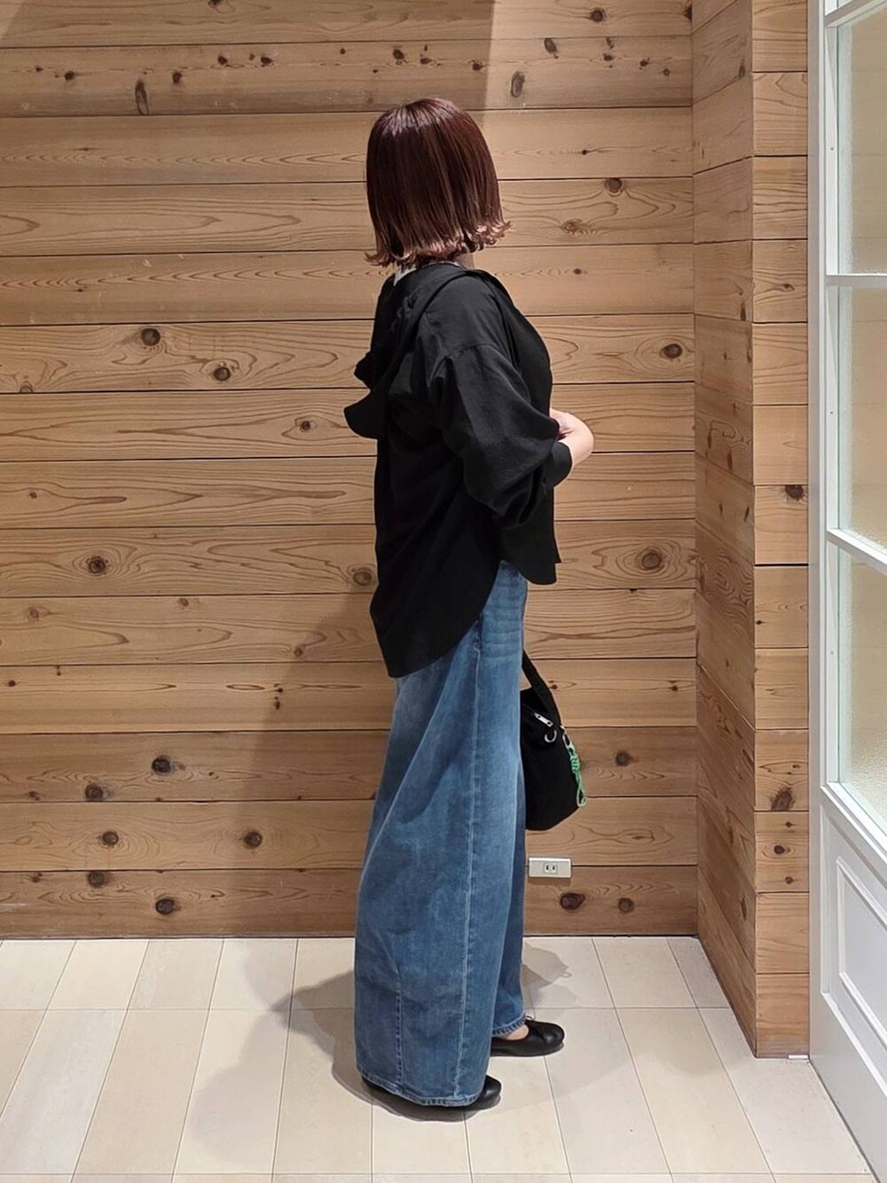 ブラック系のバレエシューズ、ブラック系のトートバッグ、ブルー系のデニムパンツを着用したレディースの春コーディネートの2枚目の写真