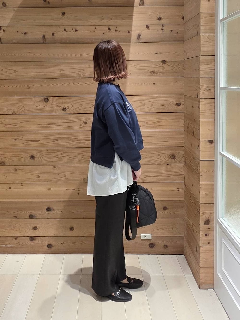 ブラック系のローファー、ブラック系のハンドバッグ、ブルー系のスウェットを着用したレディースの春コーディネートの3枚目の写真