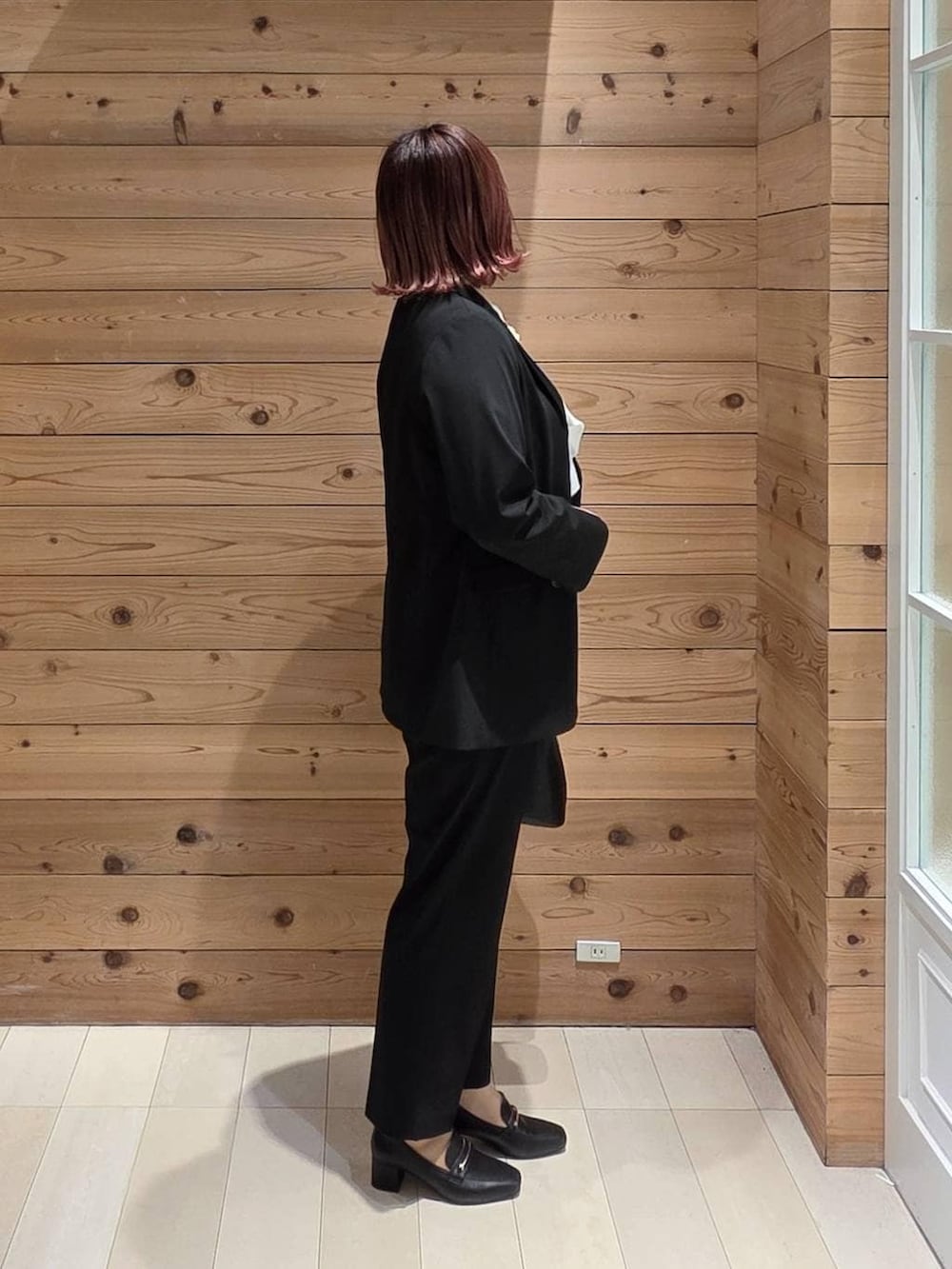 ブラック系のローファー、ブラック系のショルダーバッグ、ブラック系のスラックスを着用したレディースの冬コーディネートの2枚目の写真