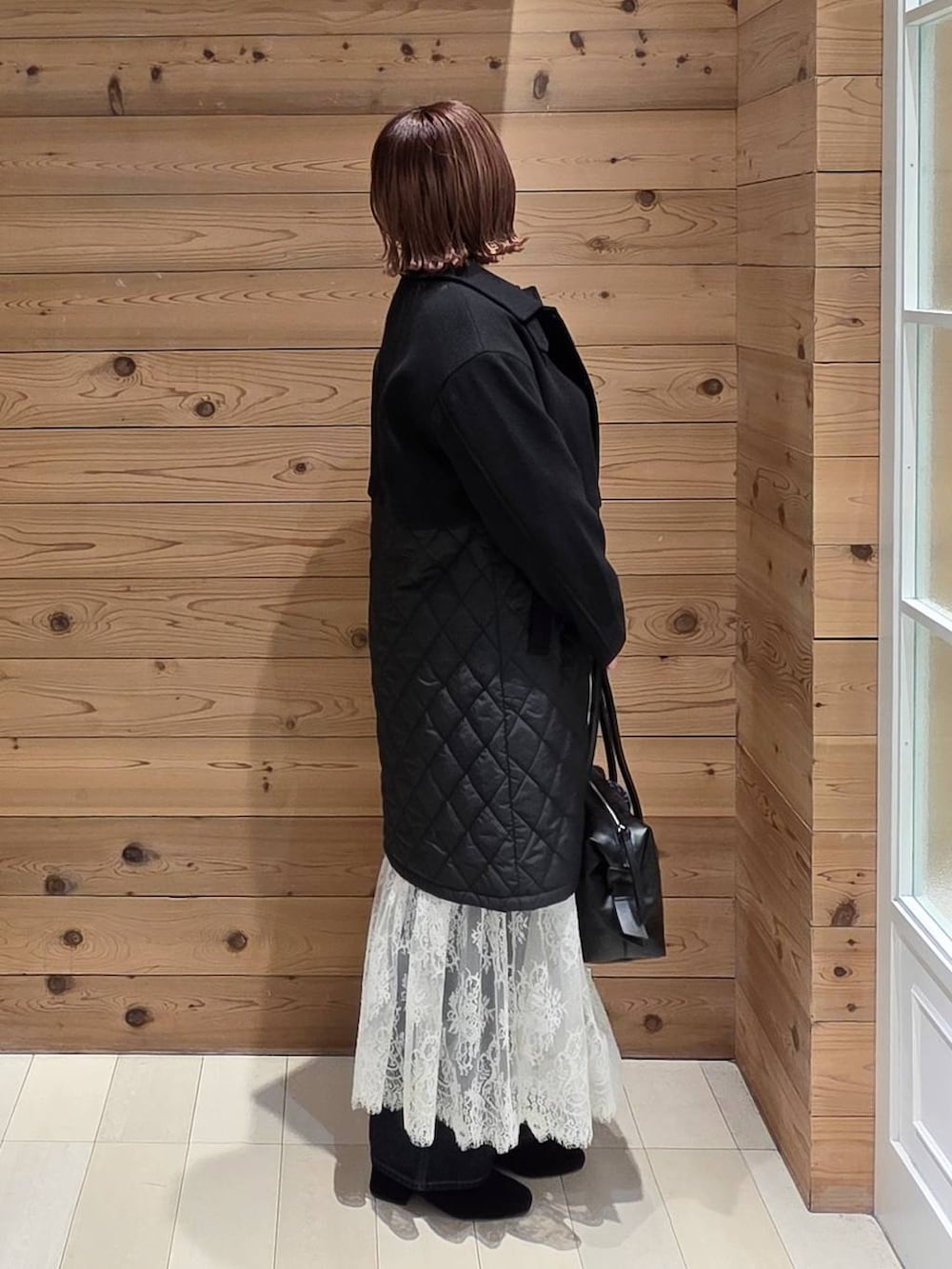 ブラック系のボストンバッグ、ブルー系のデニムパンツ、ブラック系のステンカラーコートを着用したレディースの秋コーディネートの2枚目の写真