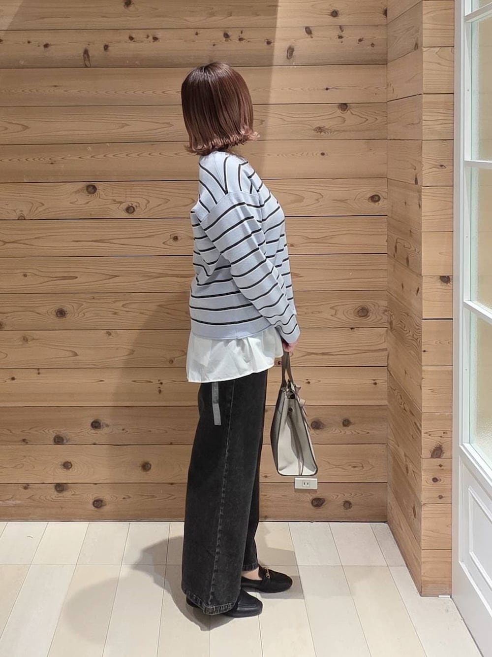 ブラック系のローファー、ホワイト系のショルダーバッグ、ブラック系のデニムパンツを着用したレディースの春コーディネートの2枚目の写真