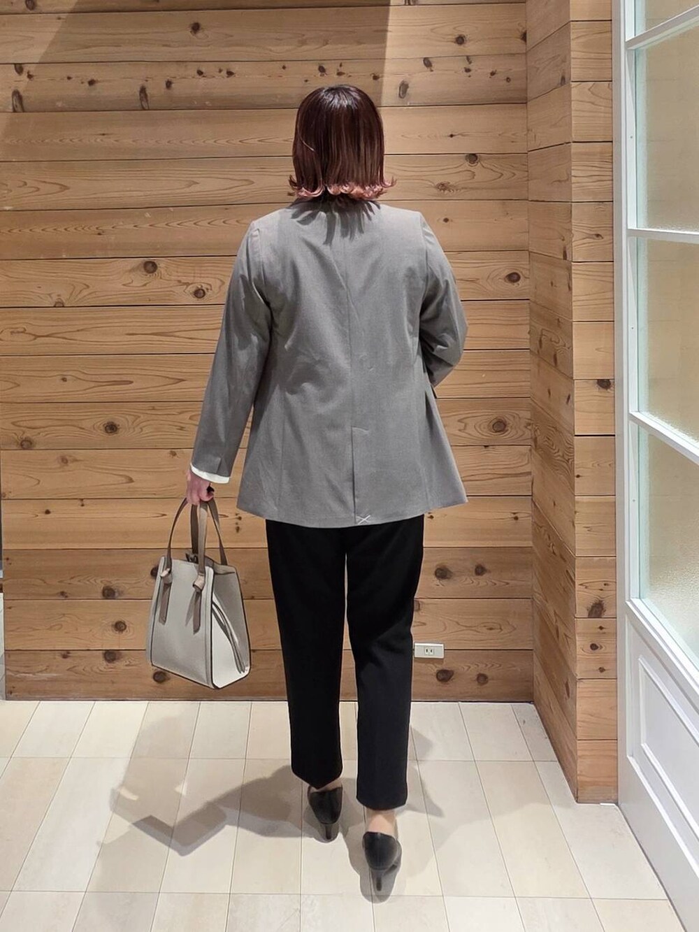 ホワイト系のショルダーバッグ、ブラック系のパンプス、ブラック系のセットアップを着用したレディースの冬コーディネートの3枚目の写真