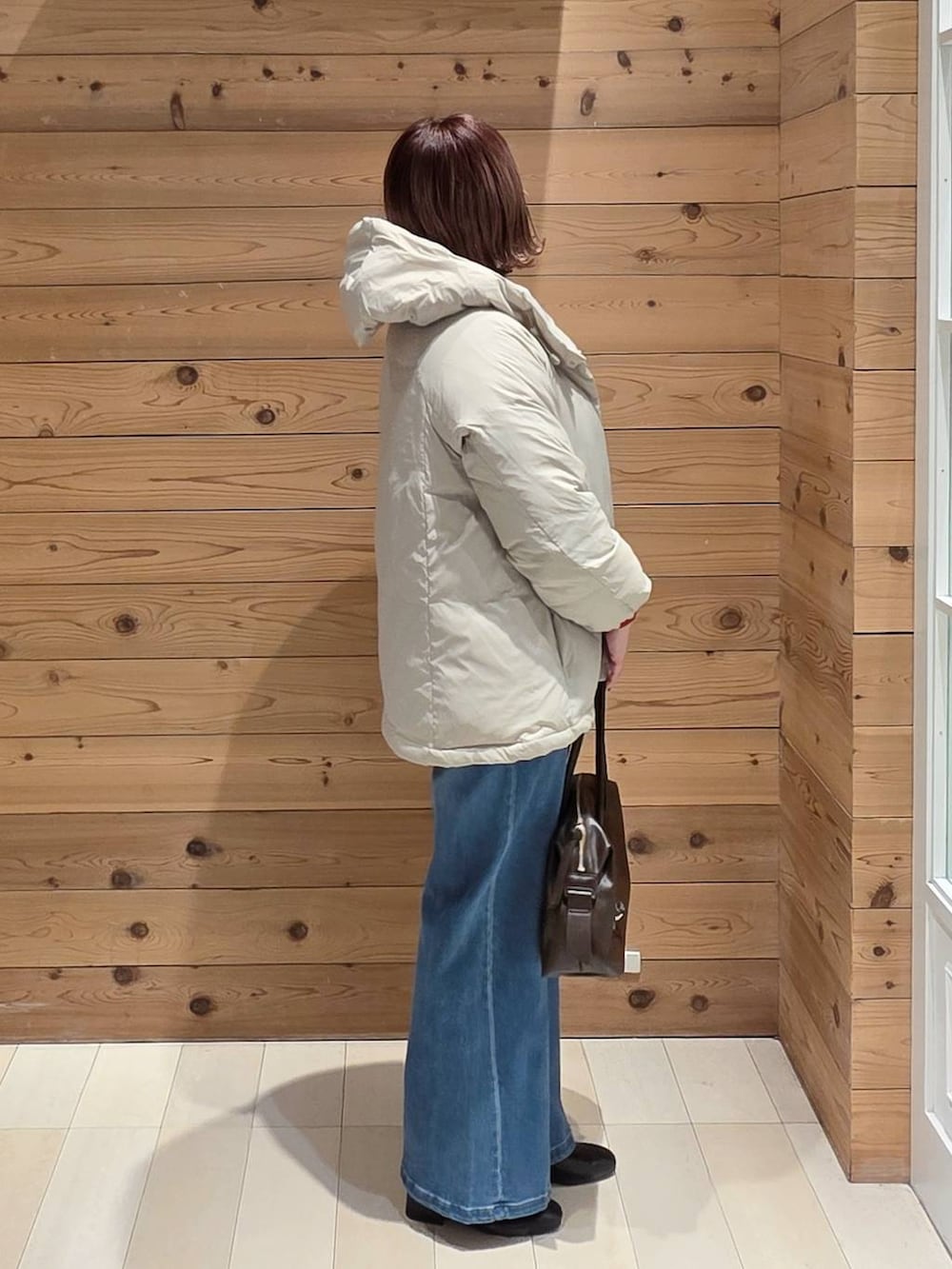 ベージュ系のダウンジャケット/コート、ブラウン系のボストンバッグ、ホワイト系のTシャツ/カットソーを着用したレディースの冬コーディネートの2枚目の写真