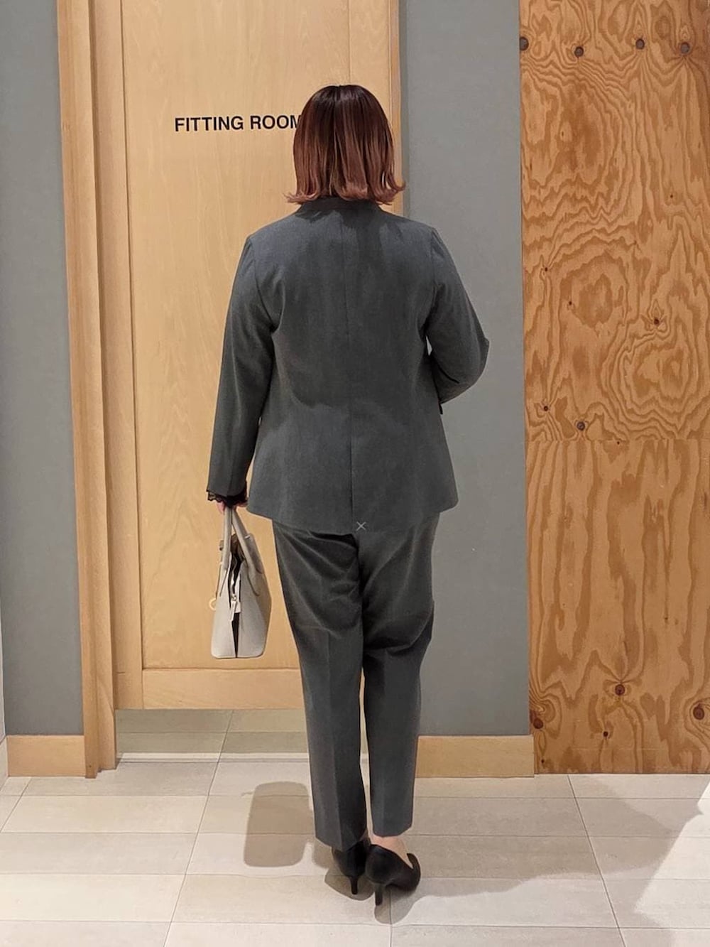 ホワイト系のショルダーバッグ、ブラック系のパンプス、グレー系のスラックスを着用したレディースの冬コーディネートの3枚目の写真