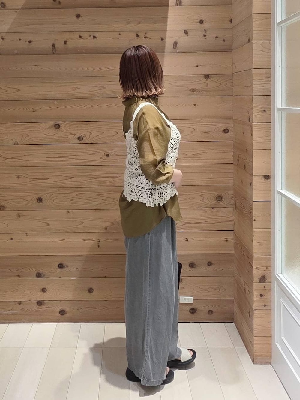 ブラック系のデニムパンツ、ブラック系のクラッチバッグ、ホワイト系のサンダルを着用したレディースの夏コーディネートの2枚目の写真