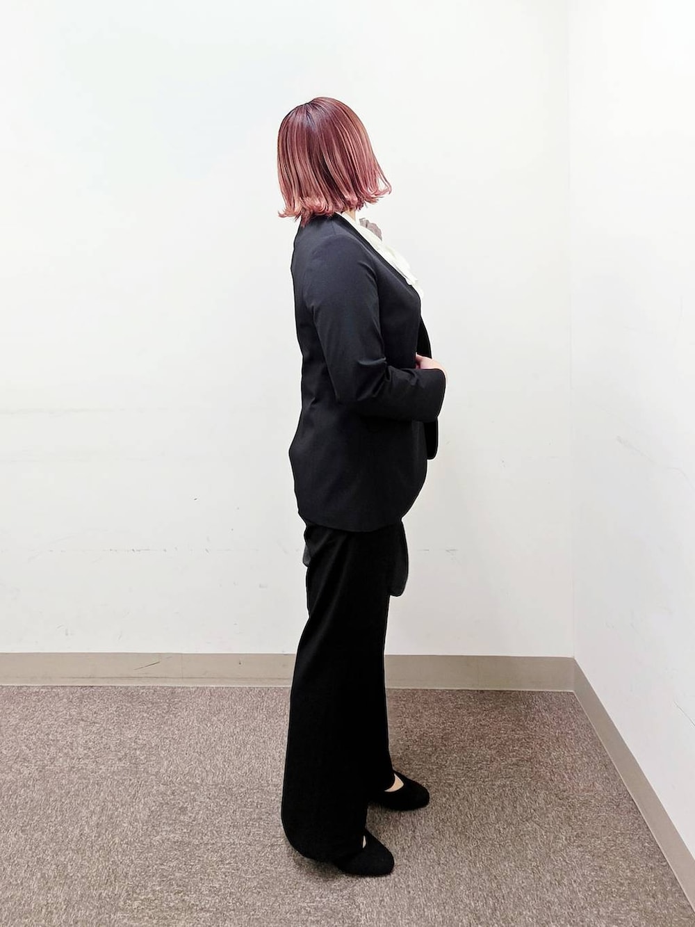 ブラック系のショルダーバッグ、ブラック系のパンプス、ブルー系のスラックスを着用したレディースの冬コーディネートの2枚目の写真