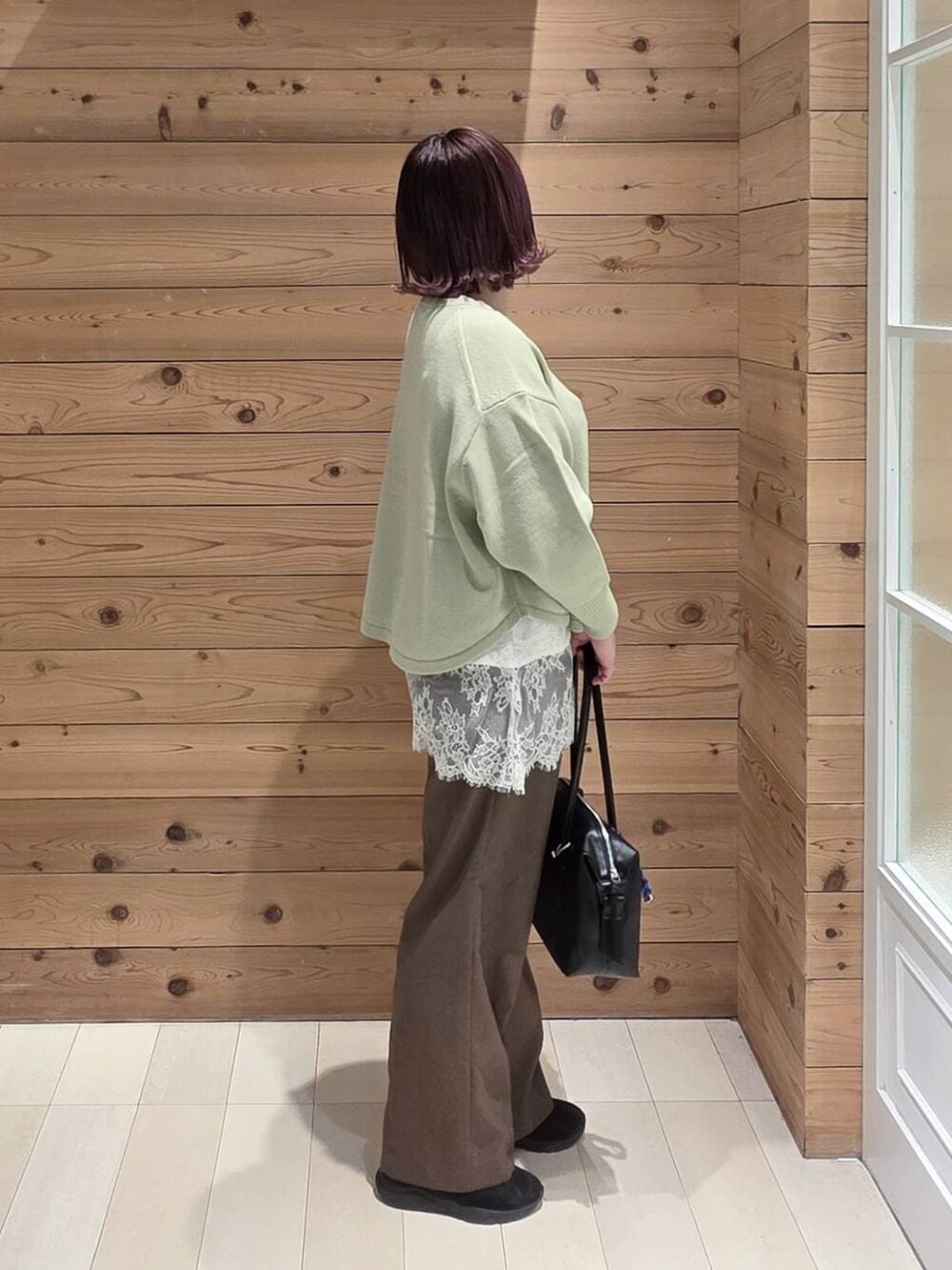 グリーン系のニット/セーター、ブラック系のダウンジャケット/コート、ブラック系のボストンバッグを着用したレディースの冬コーディネートの2枚目の写真