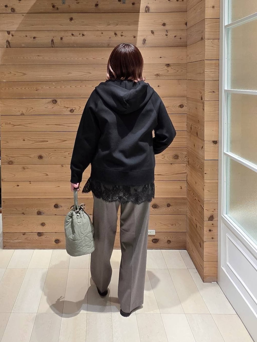 ブラック系のローファー、グリーン系のハンドバッグ、ブラック系のパーカーを着用したレディースの春コーディネートの3枚目の写真