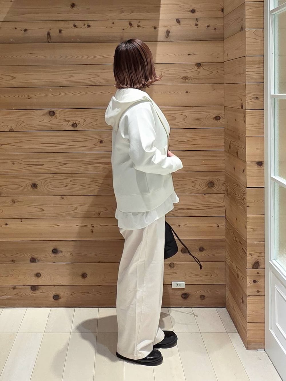 ブラック系のローファー、ブラック系のハンドバッグ、ホワイト系のパーカーを着用したレディースの春コーディネートの2枚目の写真