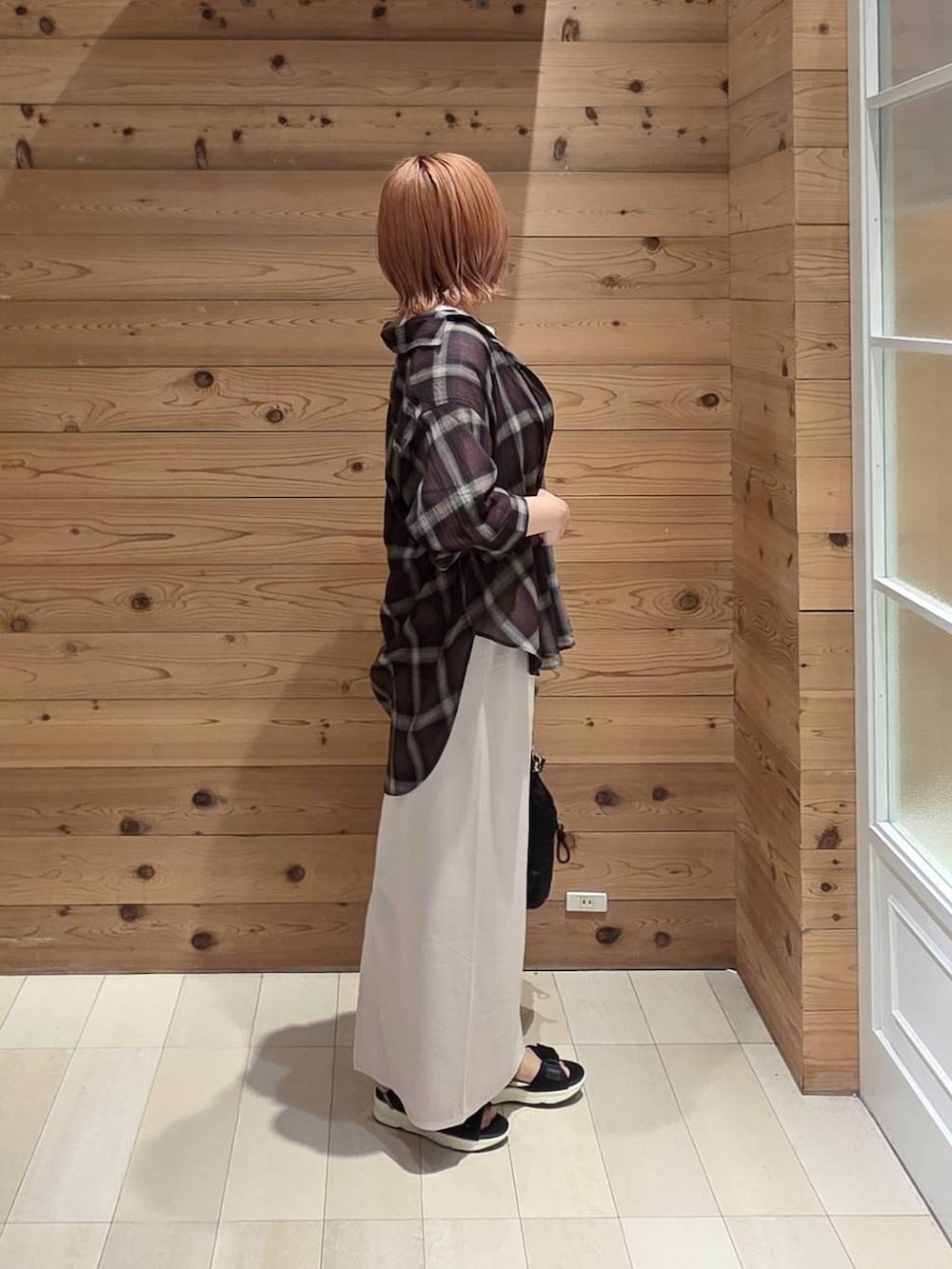 ホワイト系のスカート、ホワイト系のTシャツ/カットソー、ブラック系のサンダルを着用したレディースの夏コーディネートの2枚目の写真