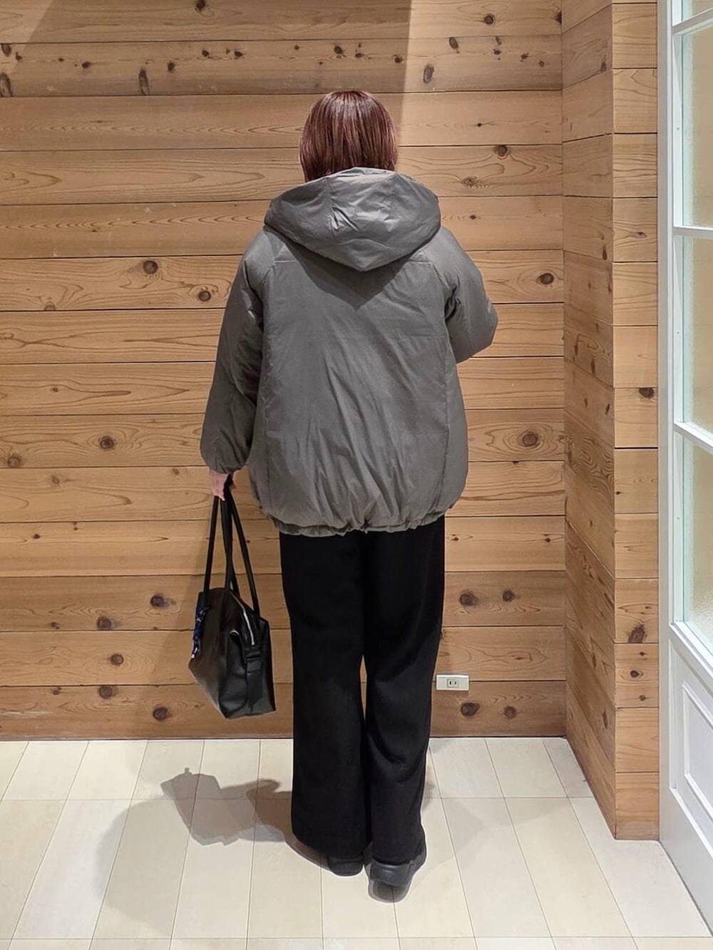 ブラウン系のダウンジャケット/コート、ブラック系のボストンバッグ、グリーン系のニット/セーターを着用したレディースの冬コーディネートの3枚目の写真