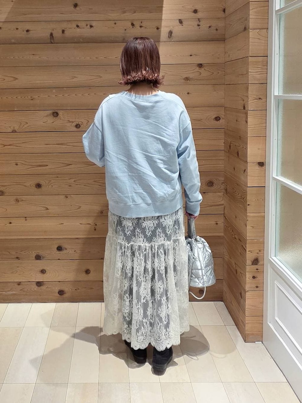 ブルー系のデニムパンツ、シルバー系のハンドバッグ、ブラウン系のワンピースを着用したレディースの春コーディネートの3枚目の写真