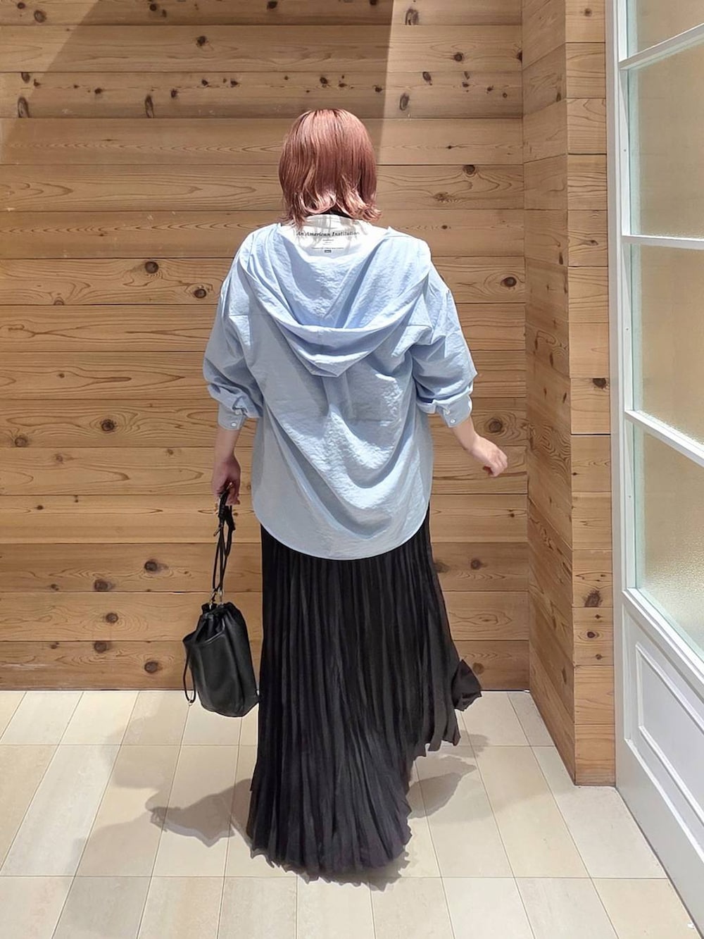 グレー系のスカート、ホワイト系のTシャツ/カットソー、ブラック系のスニーカーを着用したレディースの秋コーディネートの3枚目の写真