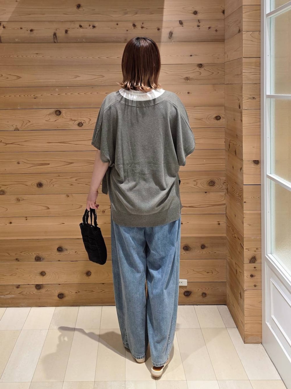 ブラウン系のカーディガン/ボレロ、ブルー系のデニムパンツ、ブラック系のクラッチバッグを着用したレディースの夏コーディネートの3枚目の写真