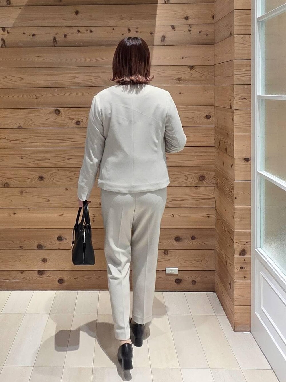 ブラック系のローファー、ブラック系のショルダーバッグ、ベージュ系のセットアップを着用したレディースの冬コーディネートの3枚目の写真