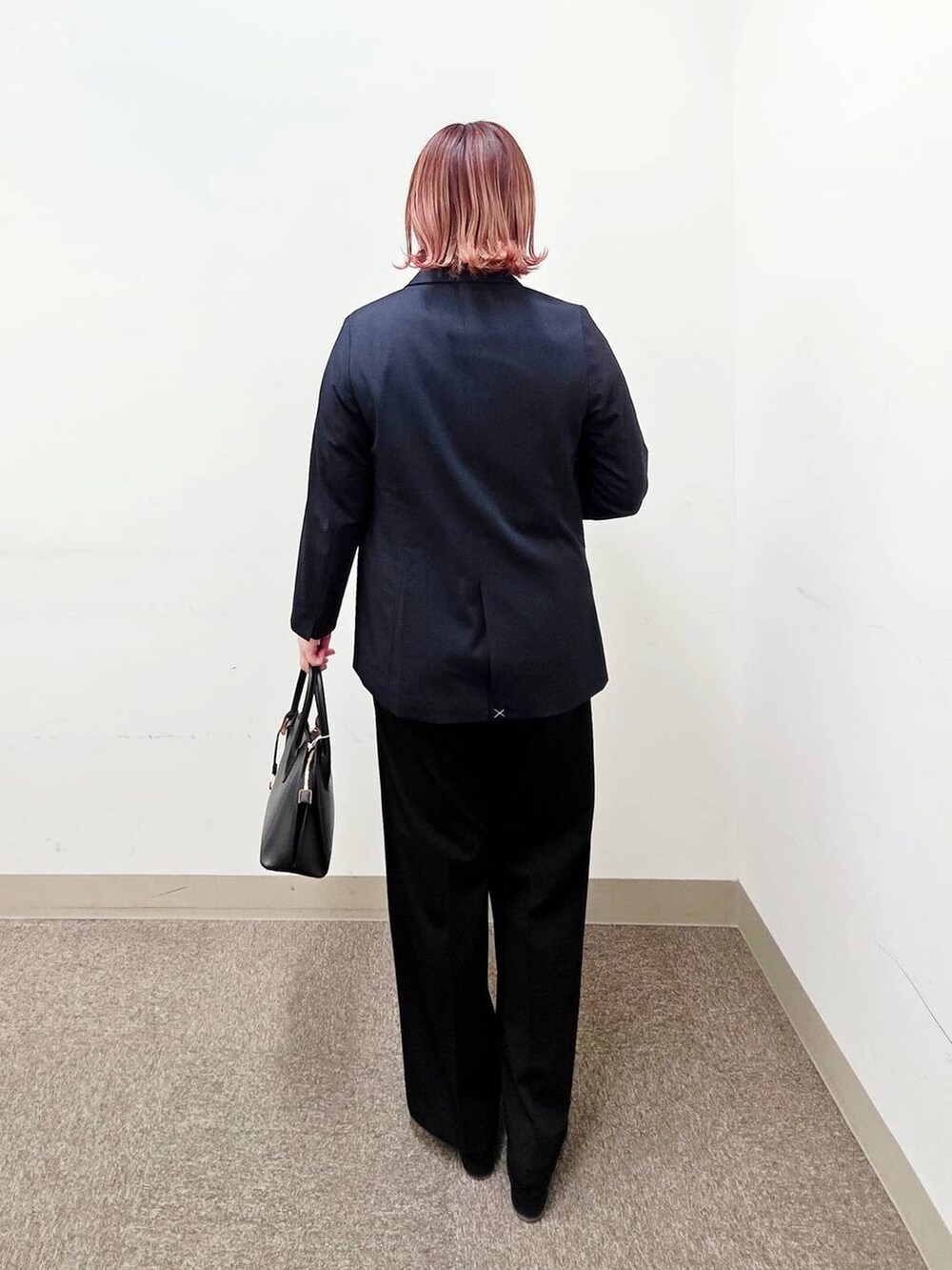 ブラック系のショルダーバッグ、ブラック系のパンプス、ブラック系のスラックスを着用したレディースの冬コーディネートの3枚目の写真