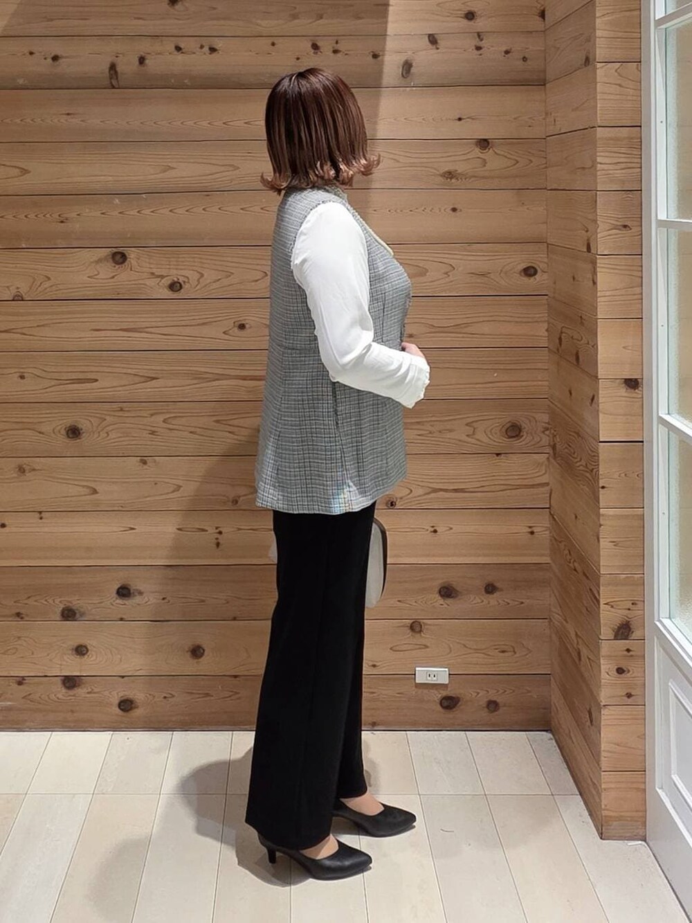 ホワイト系のショルダーバッグ、ブラック系のパンプス、ブラック系のセットアップを着用したレディースの冬コーディネートの2枚目の写真