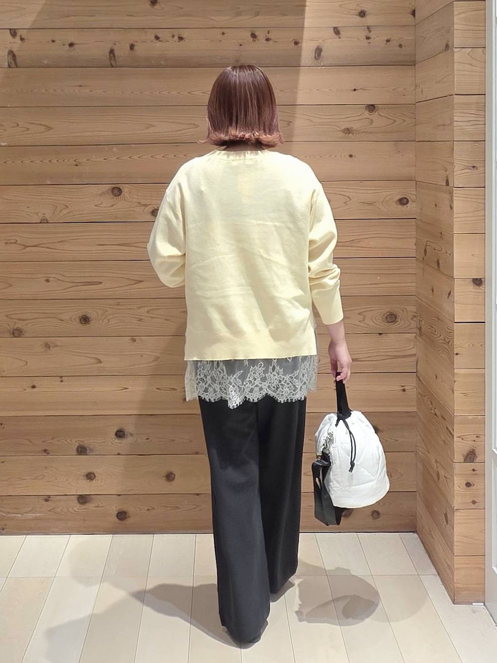 ブラック系のバレエシューズ、ホワイト系のハンドバッグ、イエロー系のニット/セーターを着用したレディースの春コーディネートの3枚目の写真