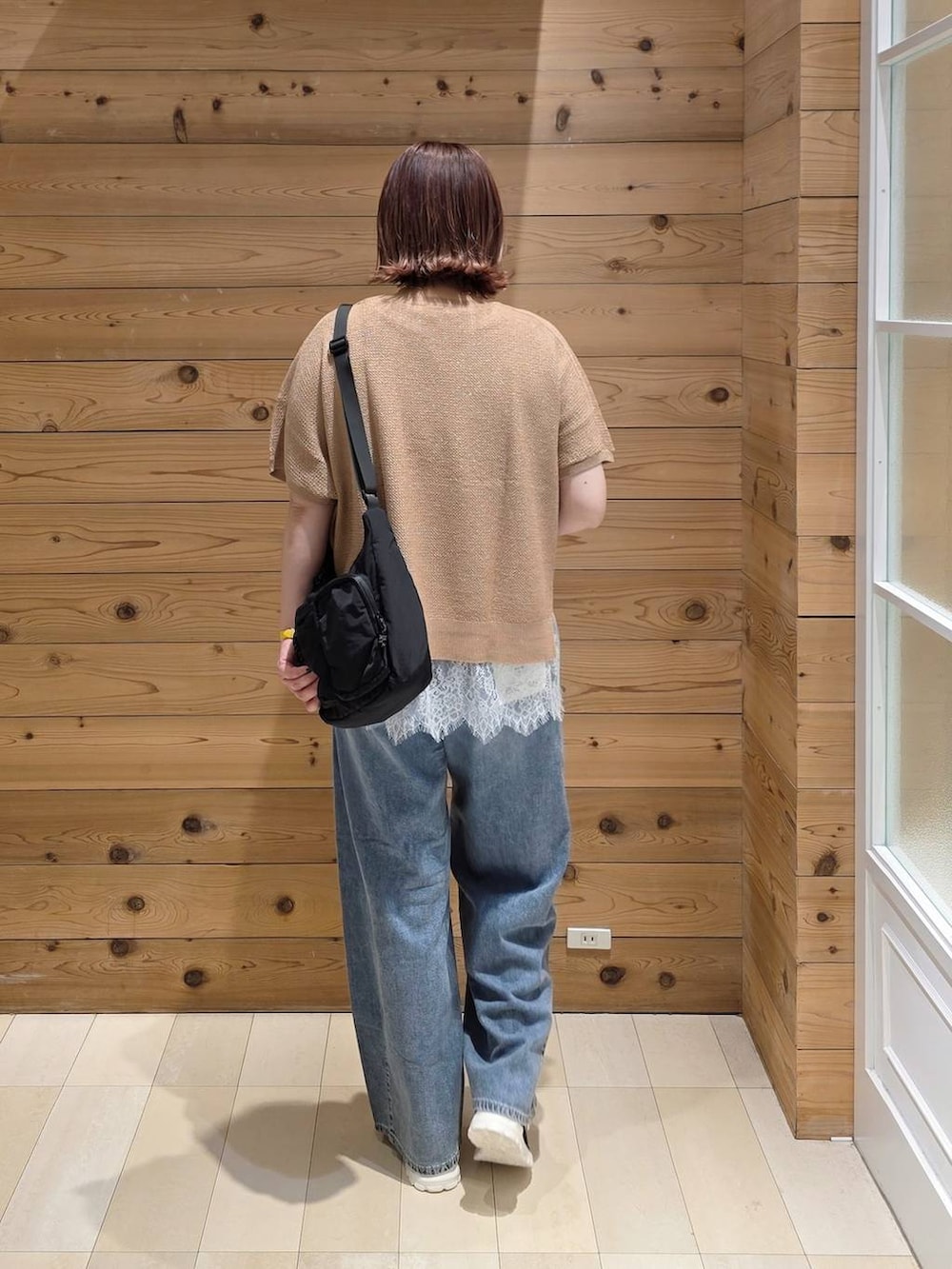 ブラック系のスニーカー、ブルー系のデニムパンツ、ブラック系のショルダーバッグを着用したレディースの春コーディネートの3枚目の写真