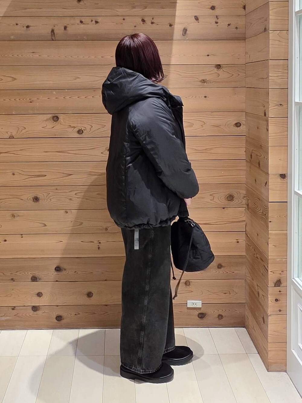 ブラック系のダウンジャケット/コート、ブラック系のデニムパンツ、ブラック系のハンドバッグを着用したレディースの冬コーディネートの2枚目の写真
