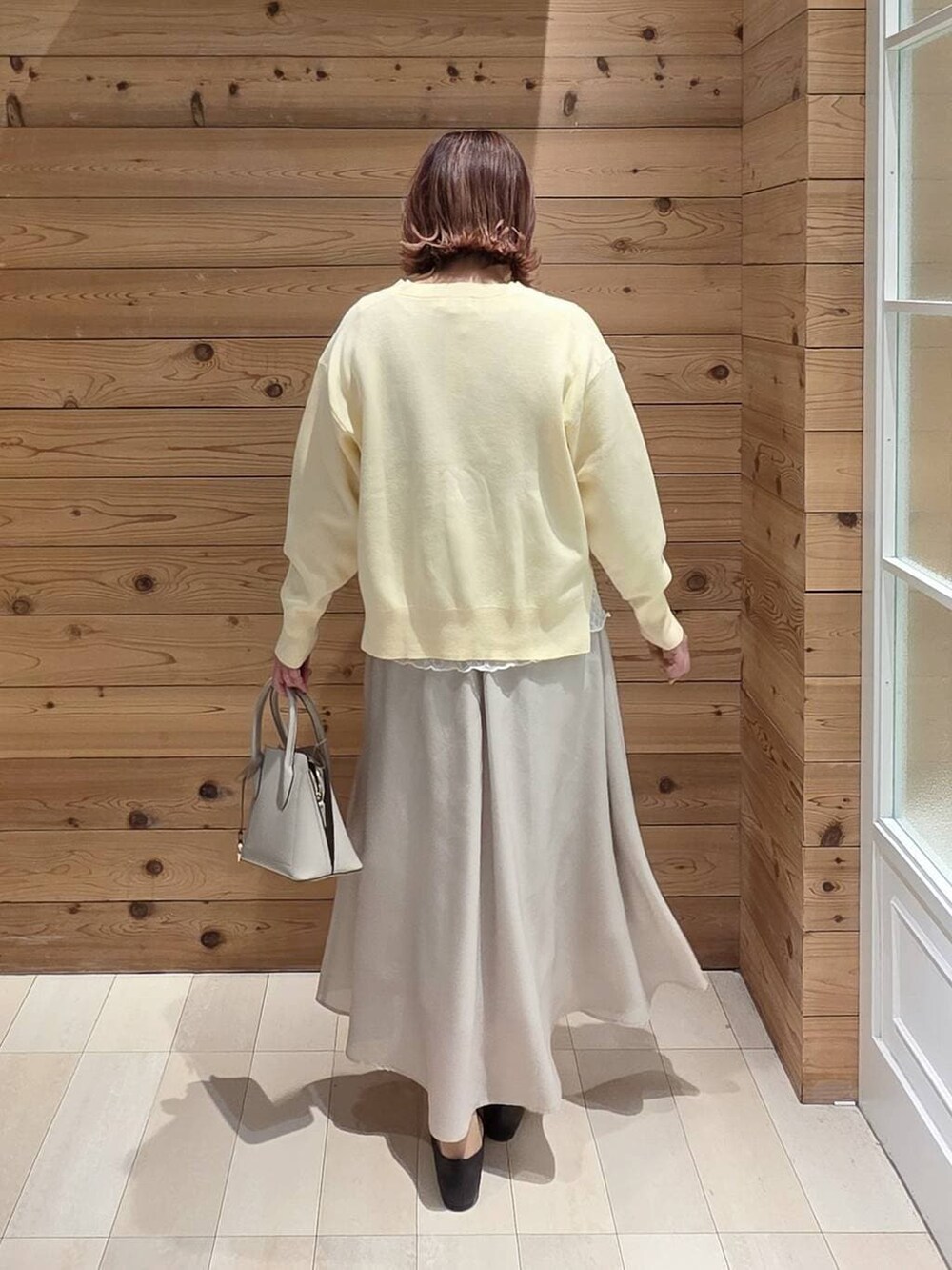 ブラック系のパンプス、ホワイト系のショルダーバッグ、ベージュ系のスカートを着用したレディースの春コーディネートの3枚目の写真