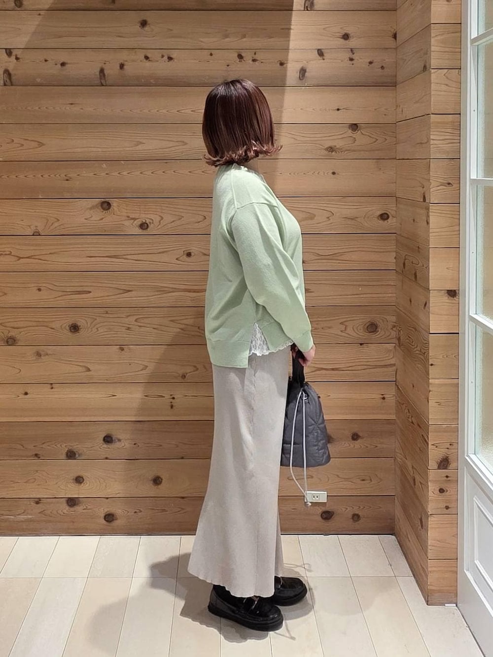 ブラック系のローファー、グレー系のハンドバッグ、ホワイト系のスカートを着用したレディースの春コーディネートの2枚目の写真