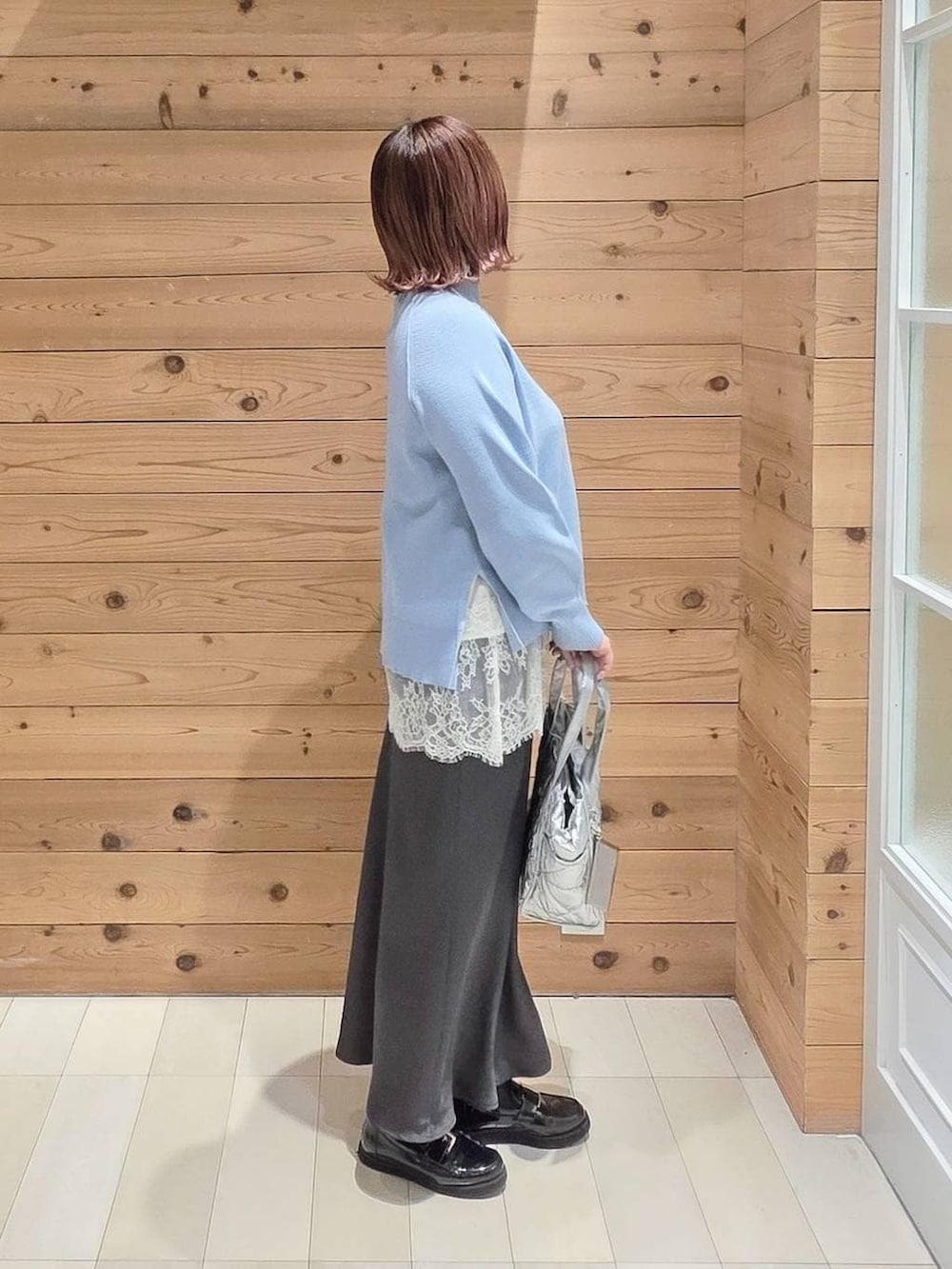 ブラック系のローファー、シルバー系のトートバッグ、ブルー系のニット/セーターを着用したレディースの冬コーディネートの2枚目の写真