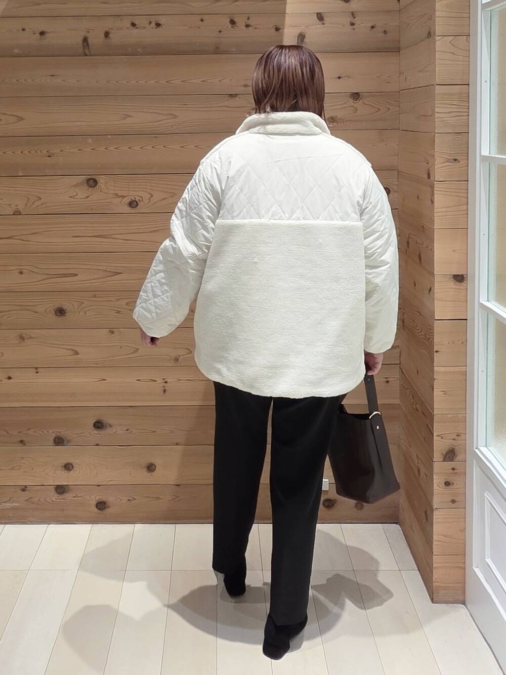 ブラウン系のショルダーバッグ、ホワイト系のブルゾン、ブラック系のその他パンツを着用したレディースの秋コーディネートの3枚目の写真