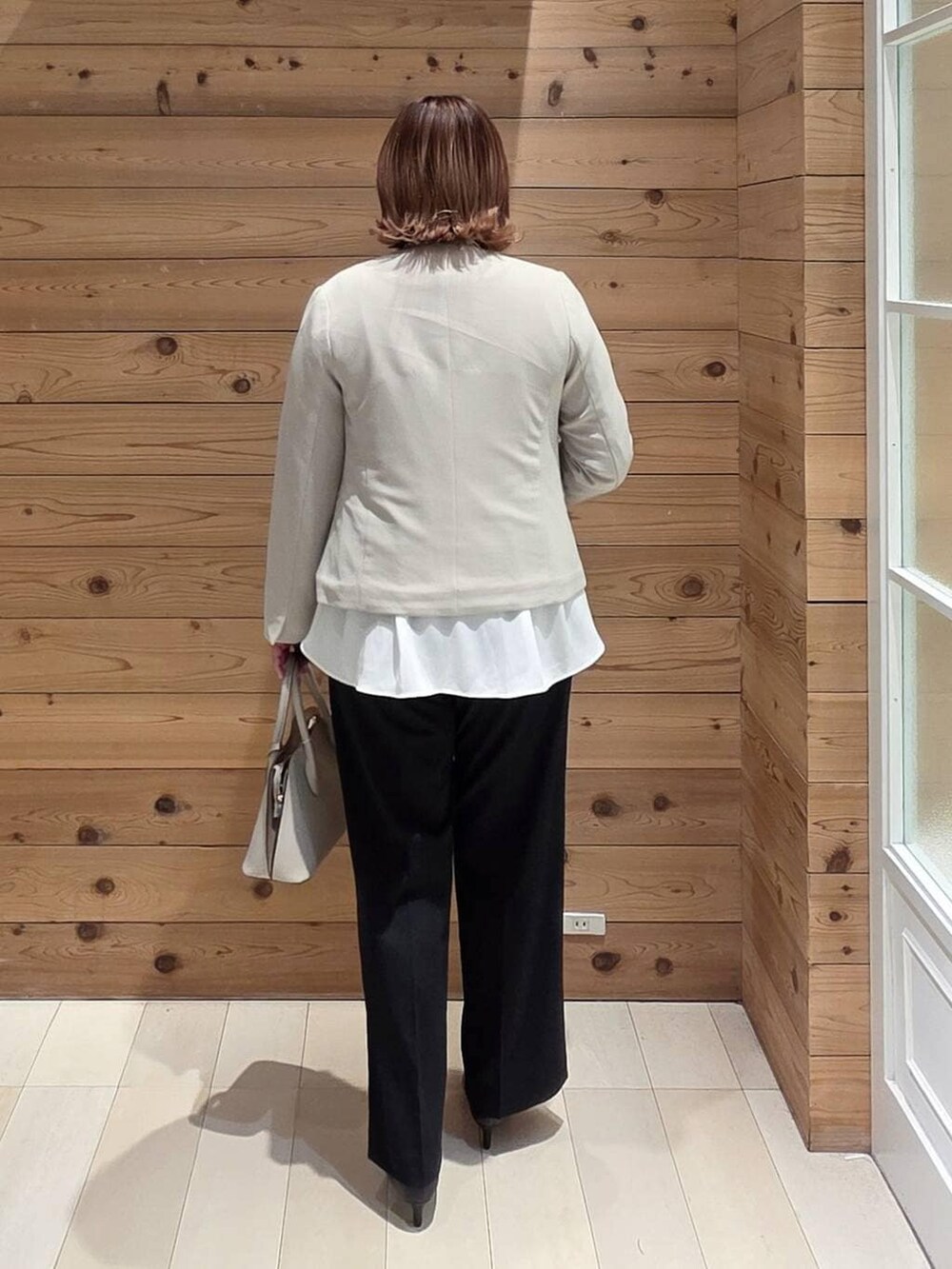 ホワイト系のショルダーバッグ、ブラック系のパンプス、ベージュ系のセットアップを着用したレディースの冬コーディネートの3枚目の写真