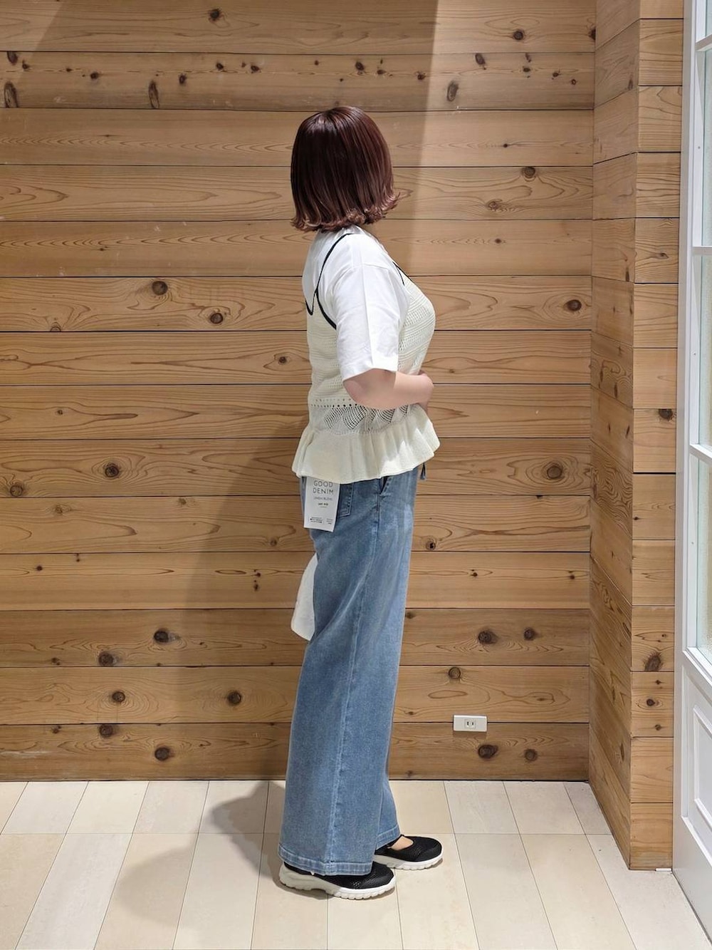 ブラック系のスニーカー、ホワイト系のハンドバッグ、ブルー系のデニムパンツを着用したレディースの春コーディネートの2枚目の写真