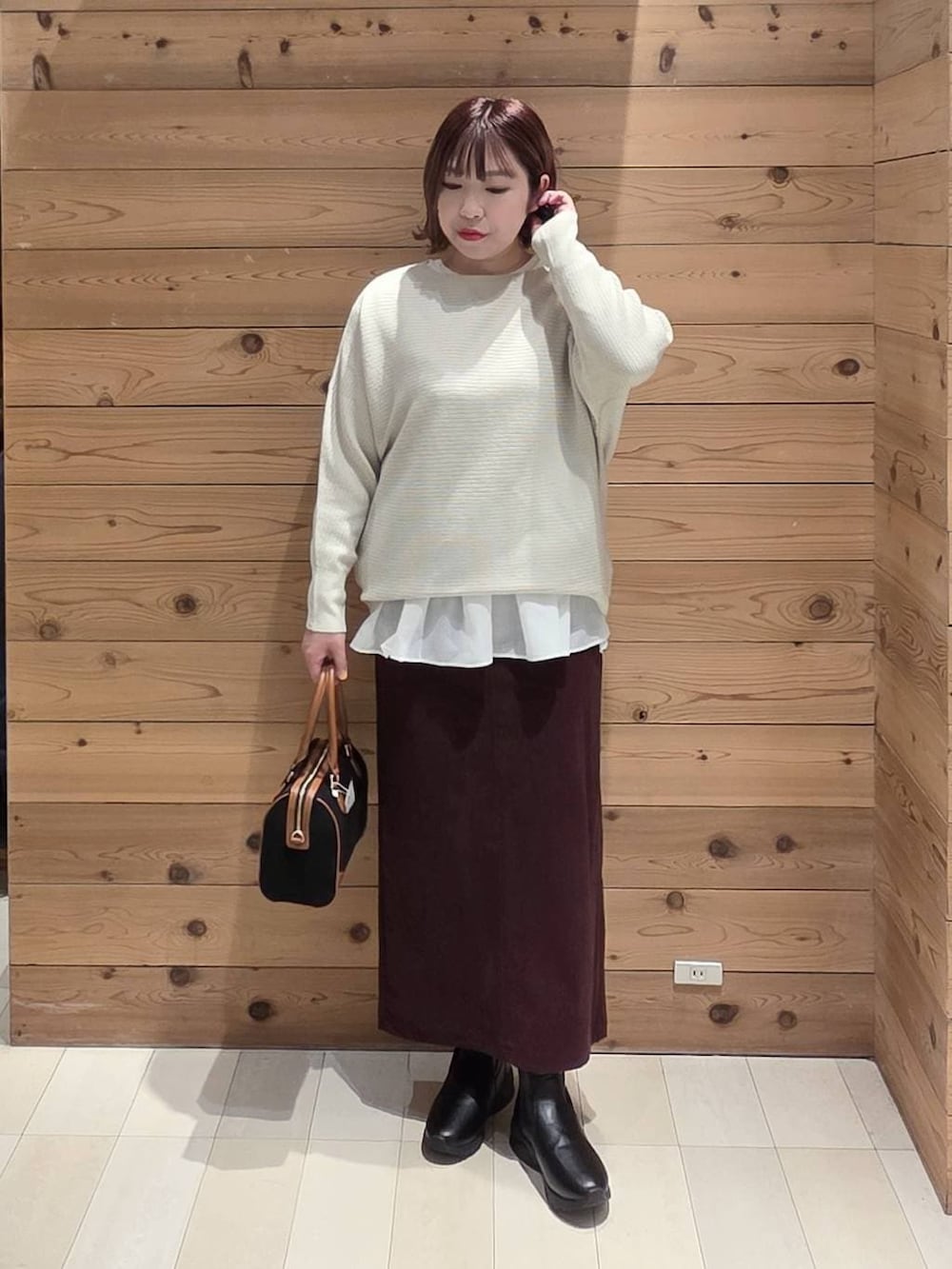 ブラック系のダウンジャケット/コート、レッド系のスカート、ブラック系のブーツを着用したレディースの冬コーディネートの4枚目の写真