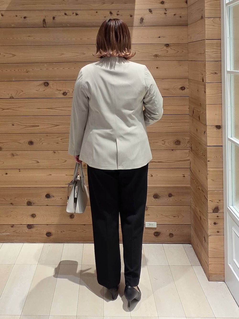 ホワイト系のショルダーバッグ、ブラック系のパンプス、ベージュ系のノーカラージャケットを着用したレディースの冬コーディネートの3枚目の写真