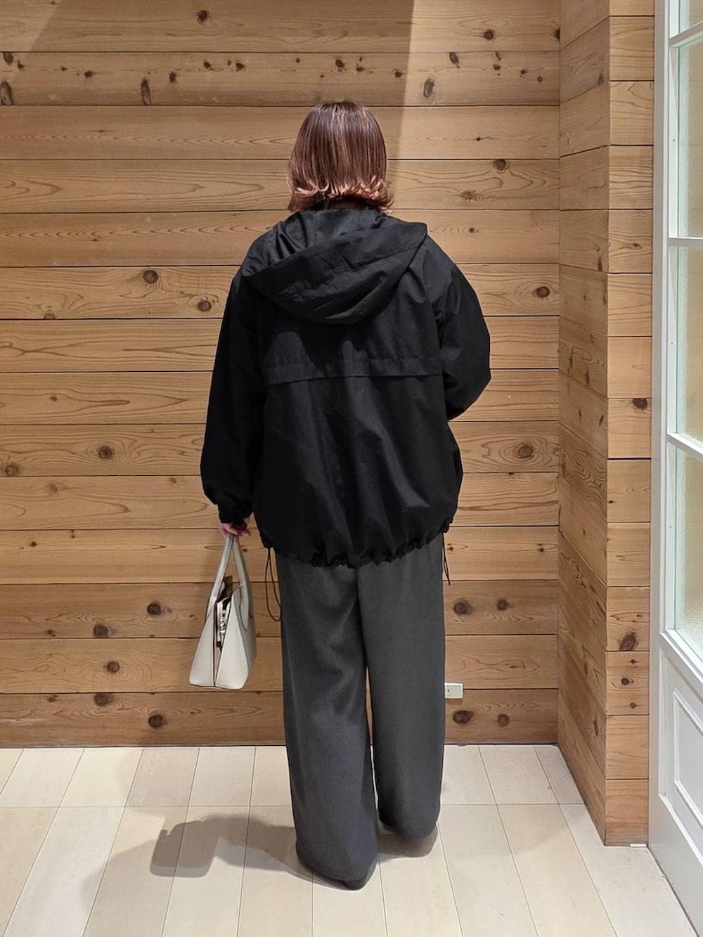 ブラック系のパンプス、ホワイト系のショルダーバッグ、ブラック系のマウンテンパーカーを着用したレディースの春コーディネートの3枚目の写真