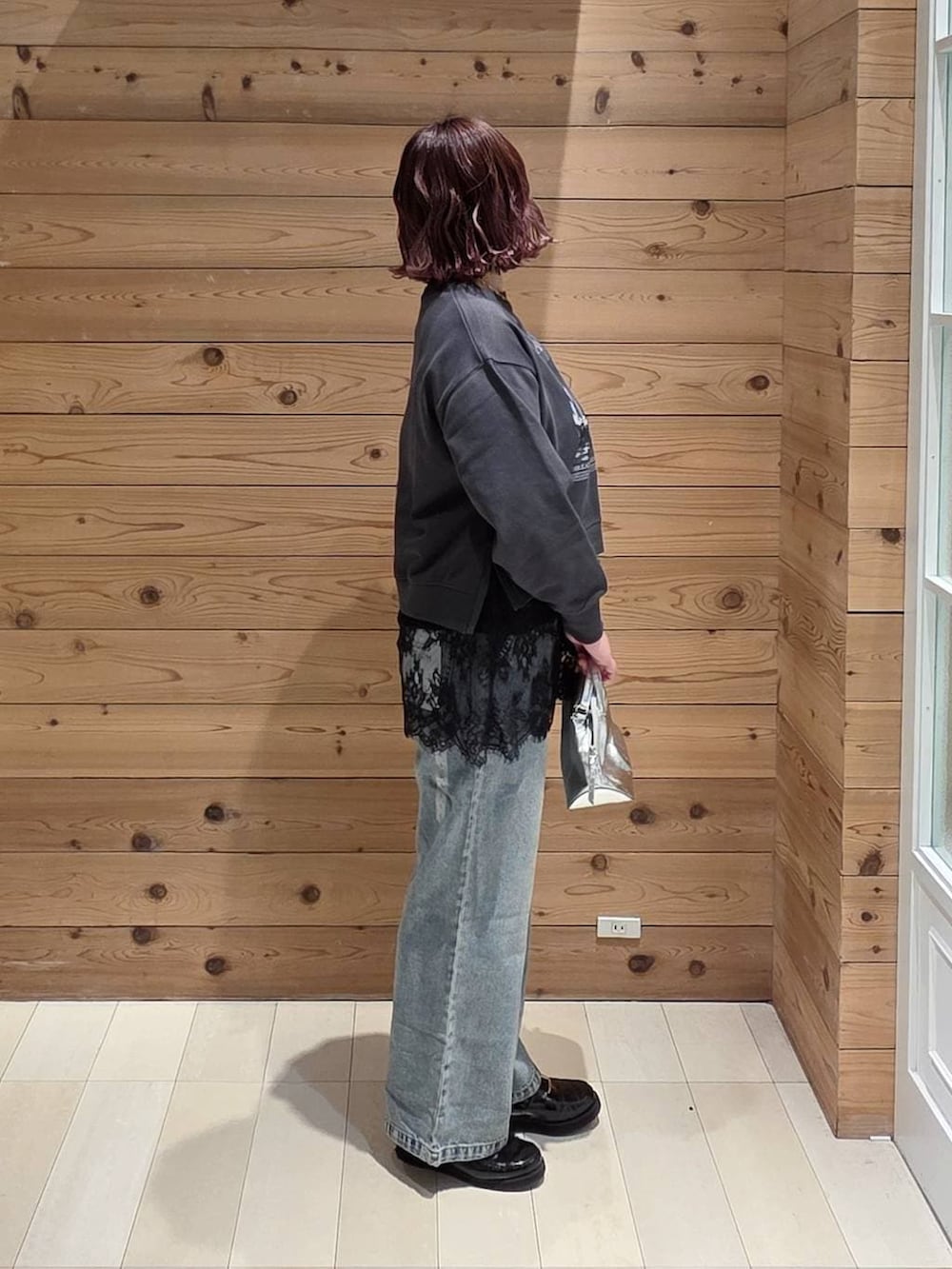 シルバー系のショルダーバッグ、ブラック系のローファー、ブルー系のデニムパンツを着用したレディースの冬コーディネートの2枚目の写真