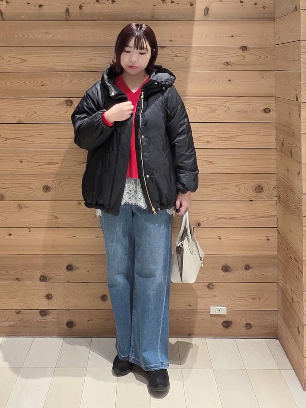 ホワイト系のショルダーバッグ、ブラック系のダウンジャケット/コート、ブラック系のブーツを着用したレディースの冬コーディネートの4枚目の写真