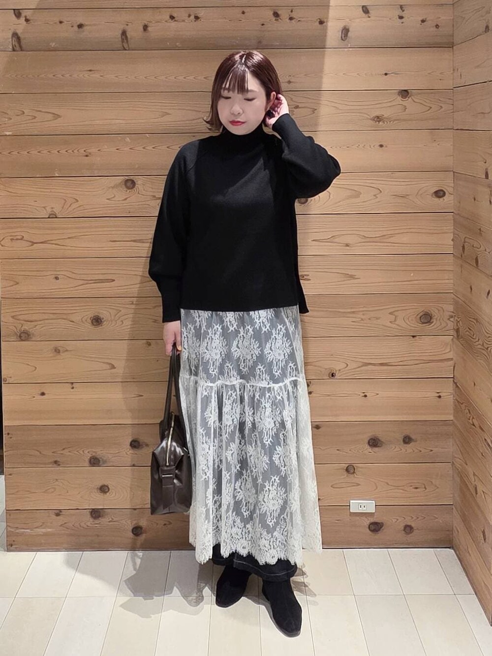 ブラウン系のボストンバッグ、ブルー系のデニムパンツ、ブラウン系のチェスターコートを着用したレディースの冬コーディネートの4枚目の写真