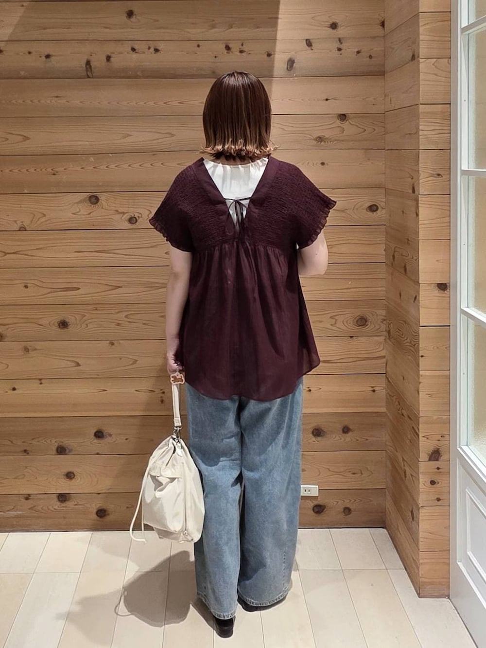 ホワイト系のショルダーバッグ、ブルー系のデニムパンツ、ホワイト系のタンクトップを着用したレディースの夏コーディネートの2枚目の写真