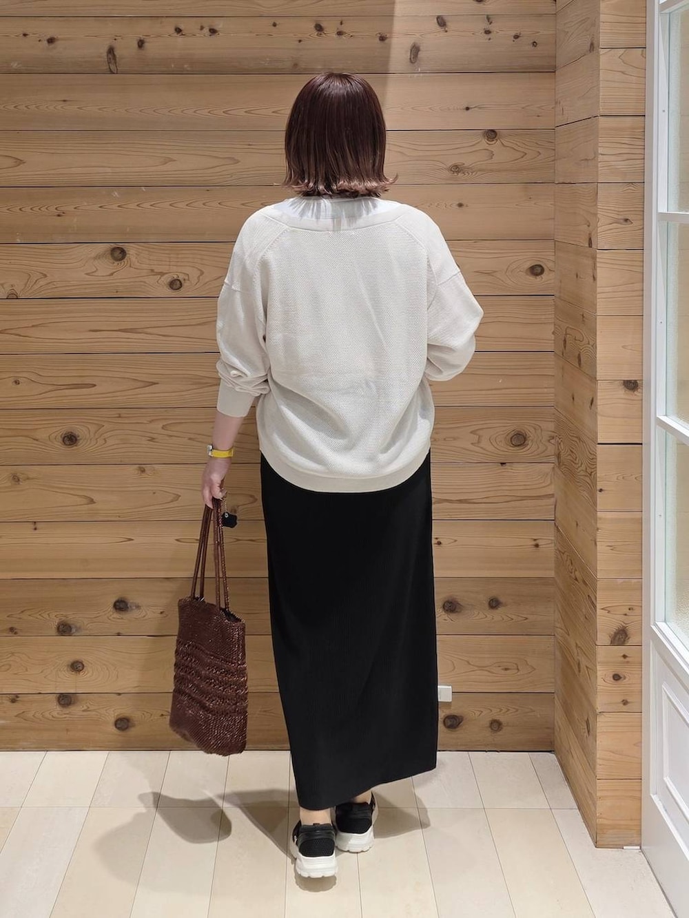 ブラック系のスニーカー、ホワイト系のTシャツ/カットソー、ブラック系のスカートを着用したレディースの春コーディネートの3枚目の写真