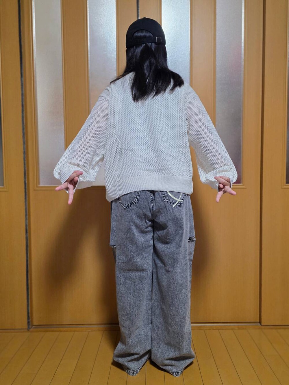 ブラック系のデニムパンツ、ホワイト系のニット/セーター、ブラック系のキャップを着用したキッズの秋コーディネートの3枚目の写真