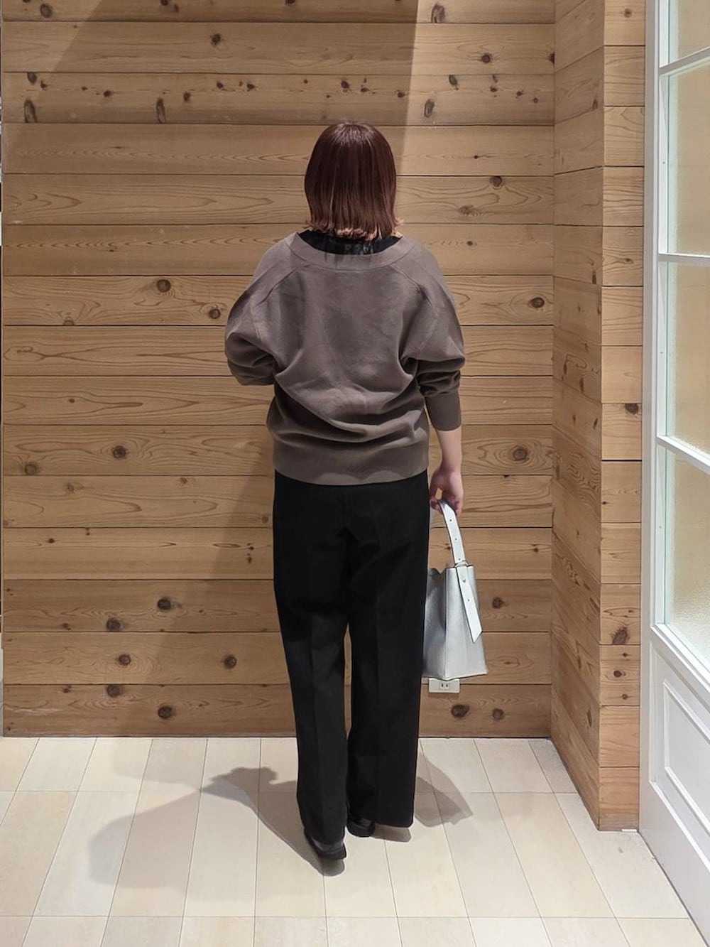 ブラック系のローファー、シルバー系のショルダーバッグ、ブラック系のスラックスを着用したレディースの春コーディネートの3枚目の写真