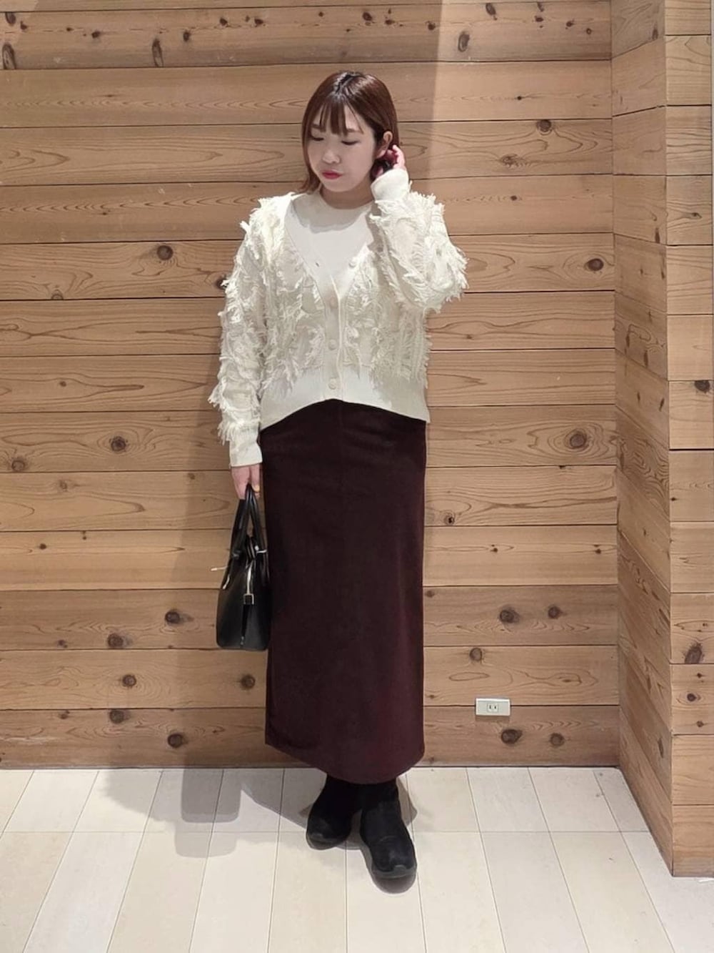 ブラック系のショルダーバッグ、ブラウン系のチェスターコート、レッド系のスカートを着用したレディースの冬コーディネートの4枚目の写真